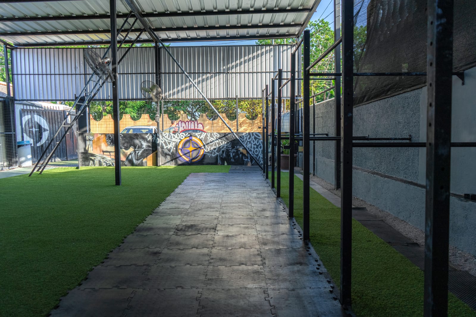 Zona central del gimnasio con pasto y mural del logo LUDUS